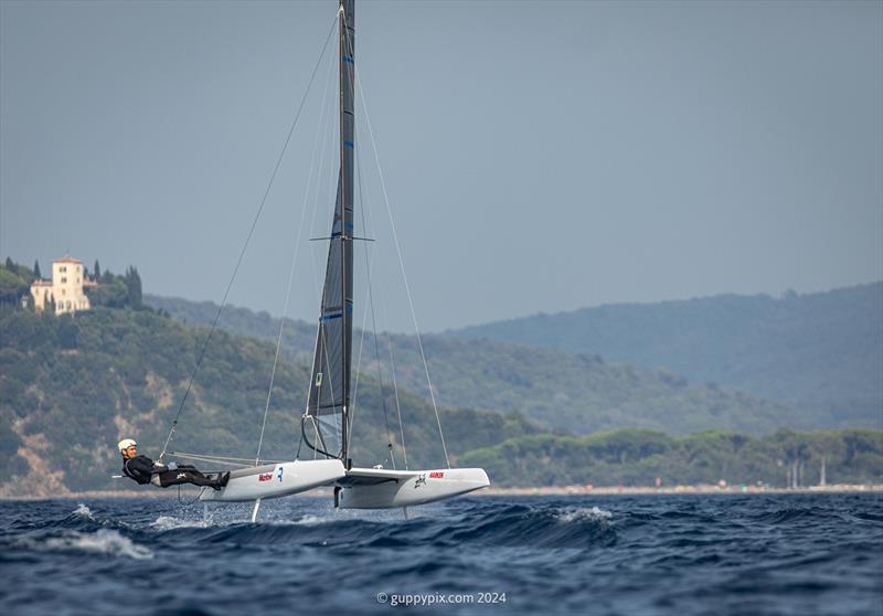 A Class Cat Regata Nazionale - The 2022 World Champ Ravi Parent USA 76 races with the iconic Punta Ala ‘White House' overlooking the Golfo Di Follonica - photo © Gordon Upton / www.guppypix.com