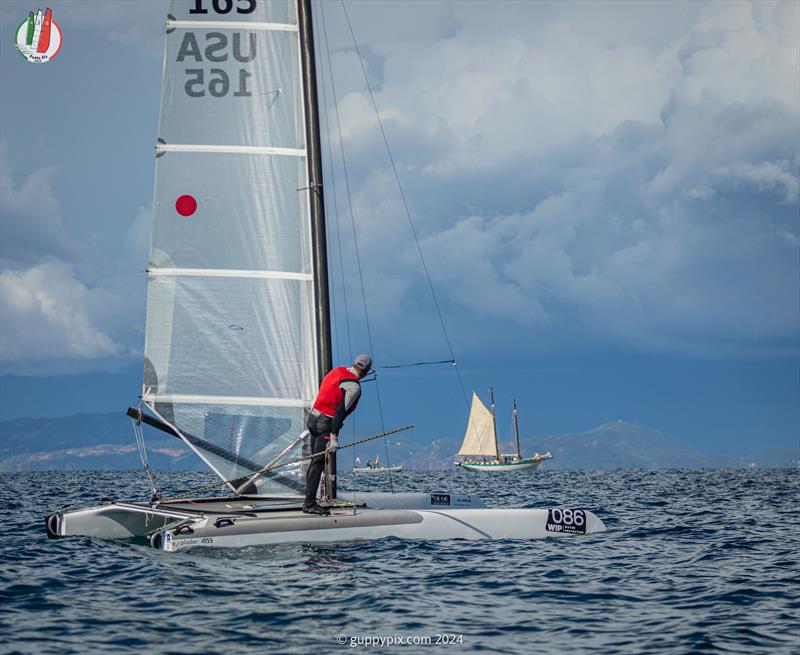 A Class Cat Worlds at Punta Ala - US Classic sailor Bob Webbon, USA 165, looks at the schooner and the impending storm - photo © Gordon Upton / www.guppypix.com